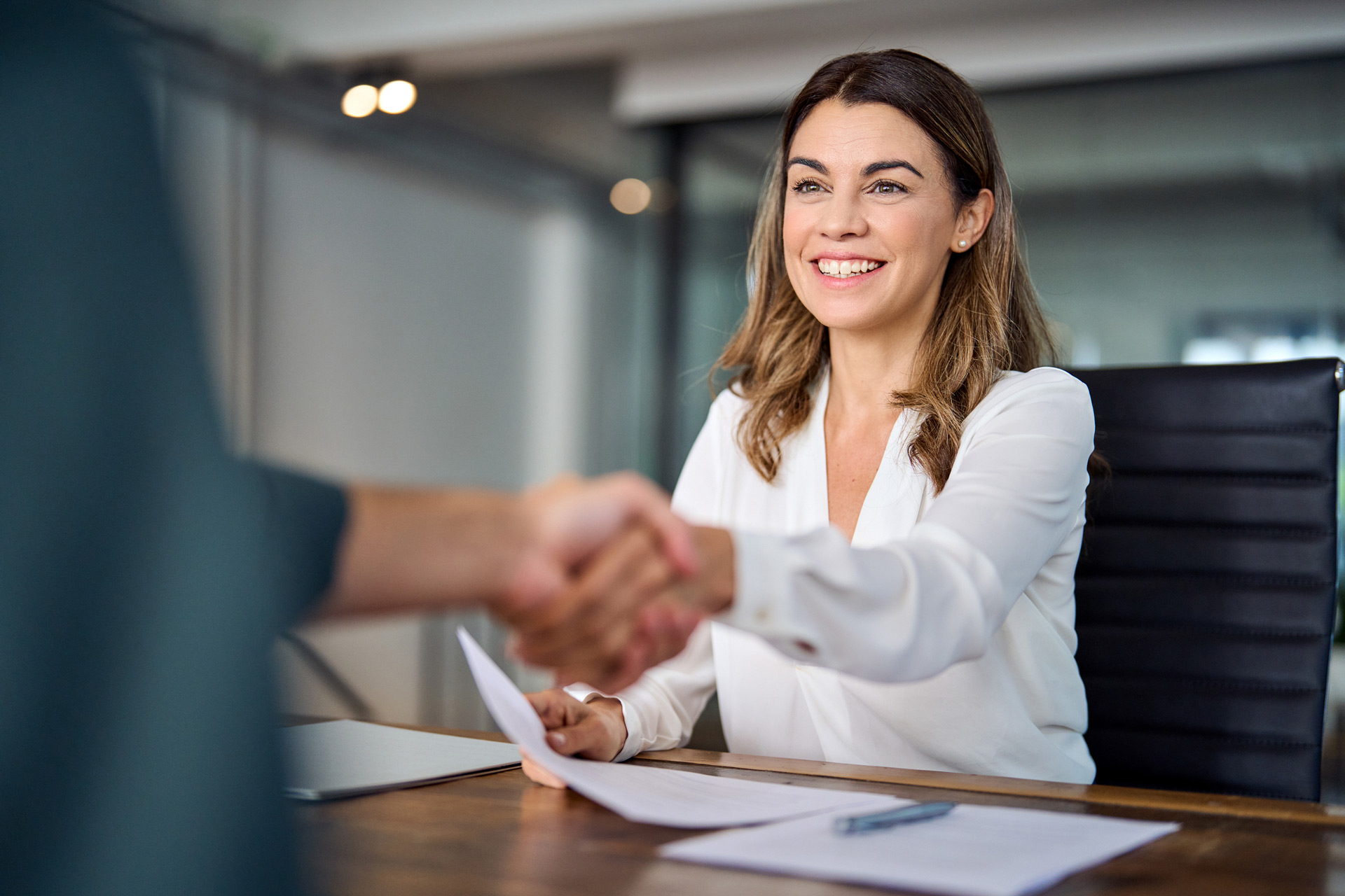 Poignée de main entre recruteuse et candidat lors d’un entretien - agence de placement à Genève.